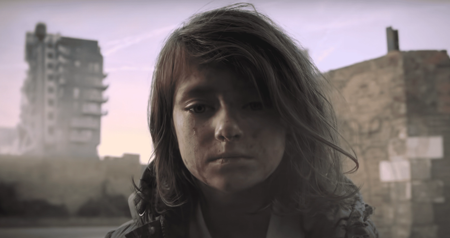 A young girl, crying, with messy hair and dirty face as she is a victim of war