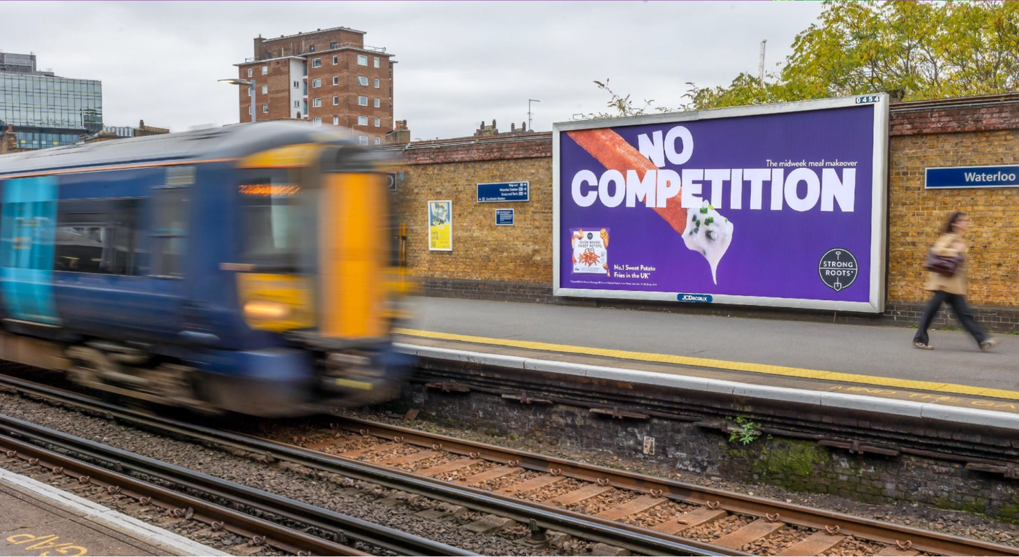 Strong Roots Sweet Potato Fries “No Competition” outdoor campaign billboard at a London train station promoting a sustainable frozen food brand.