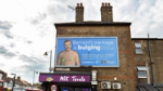 Don't Panic London's OilyFans billboard on a London building, featuring a satirical, topless image of BP CEO Bernard Looney and the text: "Bernard's package is bulging (and so is your gas bill)."