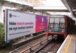 Console Connect billboard beside a DLR train in London reading 'Make instant connections, no eye contact necessary'.