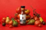 A bottle of Rubies tomato ketchup surrounded by fresh ingredients of tomatoes and pears