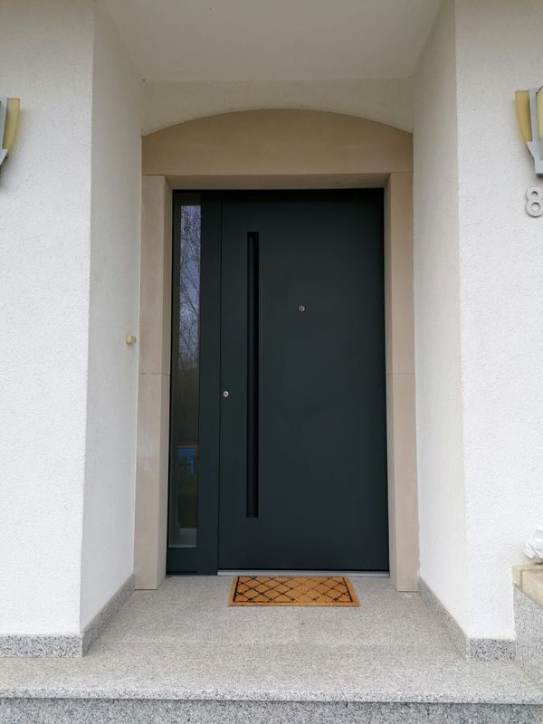 Anthrazit Haustür mit eingelassener Griffmulde und schmalem Seitenteil unter Rundbogen, Granitstufen