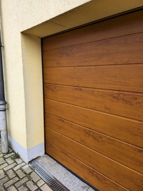 Schrägansicht aus der Nähe: Sektionaltor in Golden Oak mit Sicken, hellgelbe Fassade