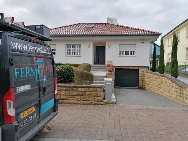 Weißer Bungalow mit rotem Ziegeldach, anthrazitfarbener Haustür und Sektionaltor