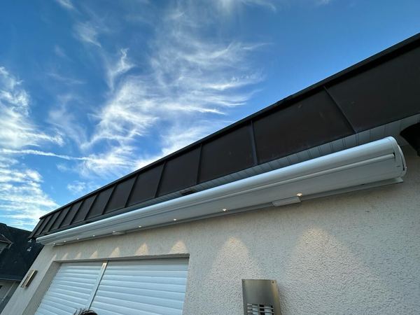 Geschlossene weiße Kassettenmarkise mit LED-Spots über Garagentoren