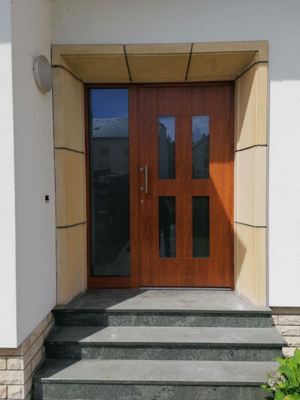 Haustür in Golden-Eiche-Optik mit vier Glasfeldern und Seitenteil, Sandsteingewände und Steinstufen