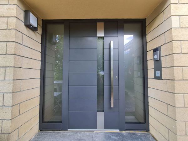 Anthrazit Haustür mit Rillen und mittigem Glasstreifen, zwei Seitenteile, Wände aus Kalksandstein