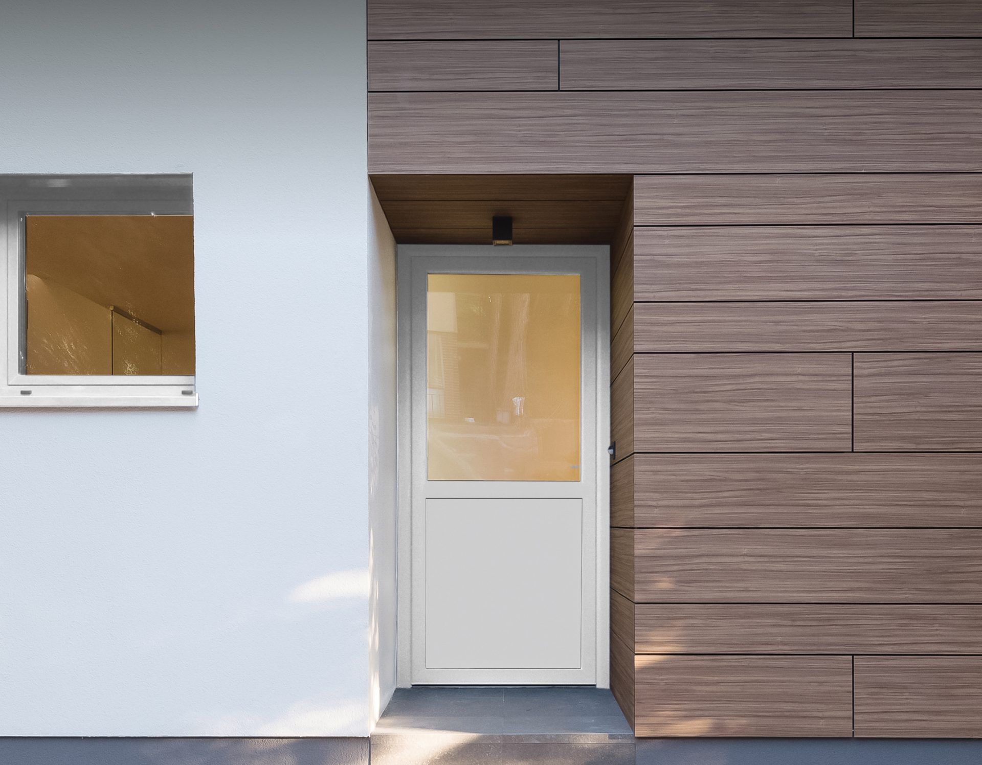 Weiße Schüco-Nebentür mit Glasfeld im oberen Teil, eingebaut zwischen Putzwand und Holzverkleidung