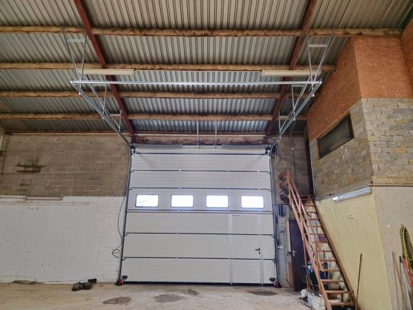 Hellgraues Industrie-Sektionaltor mit Fensterreihe und Schlupftür, Innenansicht einer Halle