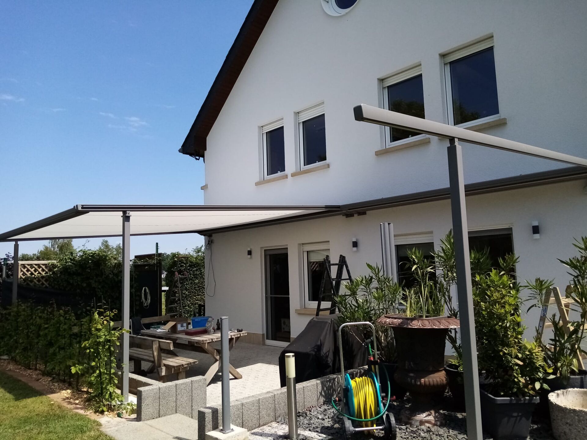 Weiße Pergolamarkise auf Stützen, Gesamtansicht eines weißen Giebelhauses
