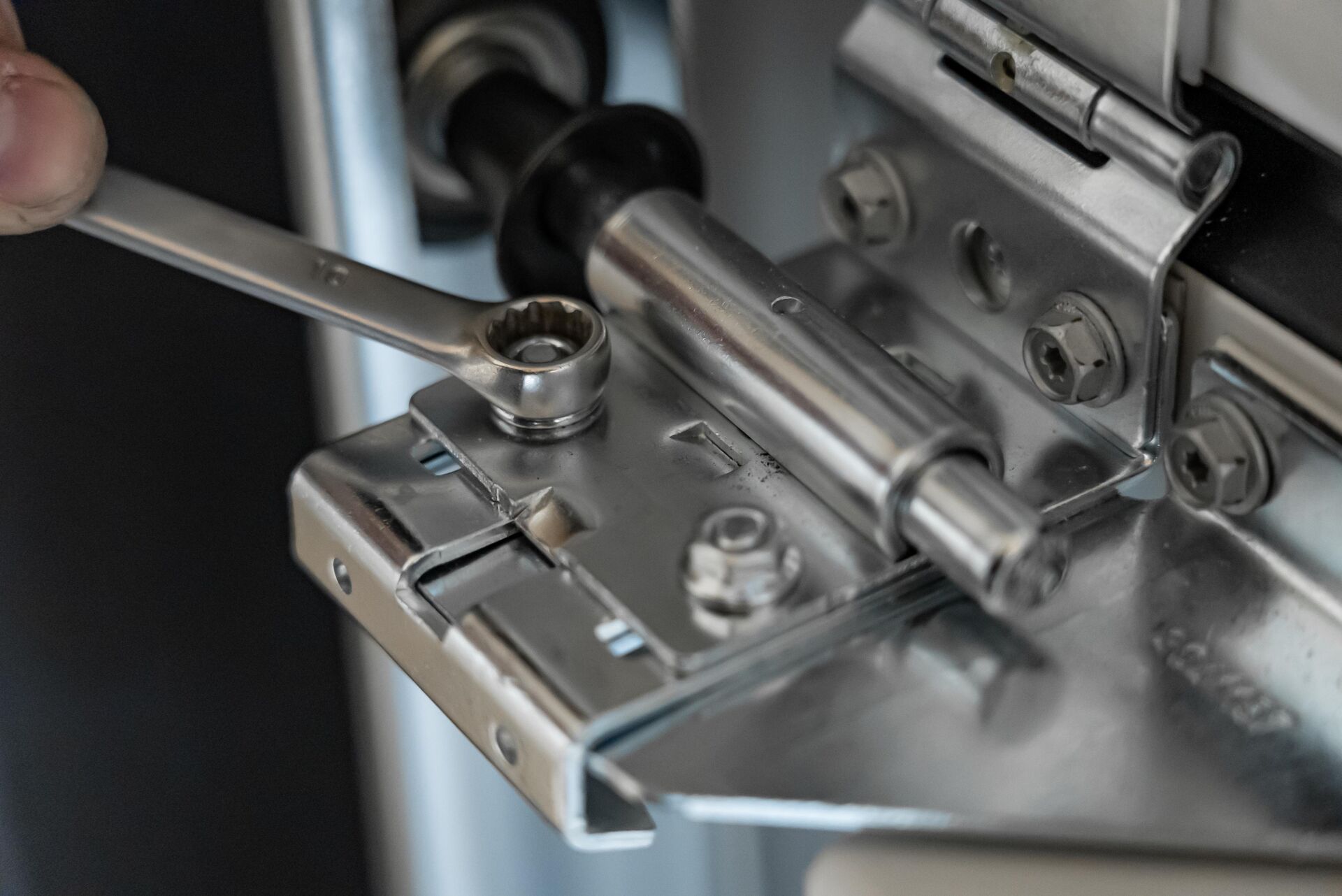 Close-up of a spanner adjusting the hinge and roller of a sectional garage door