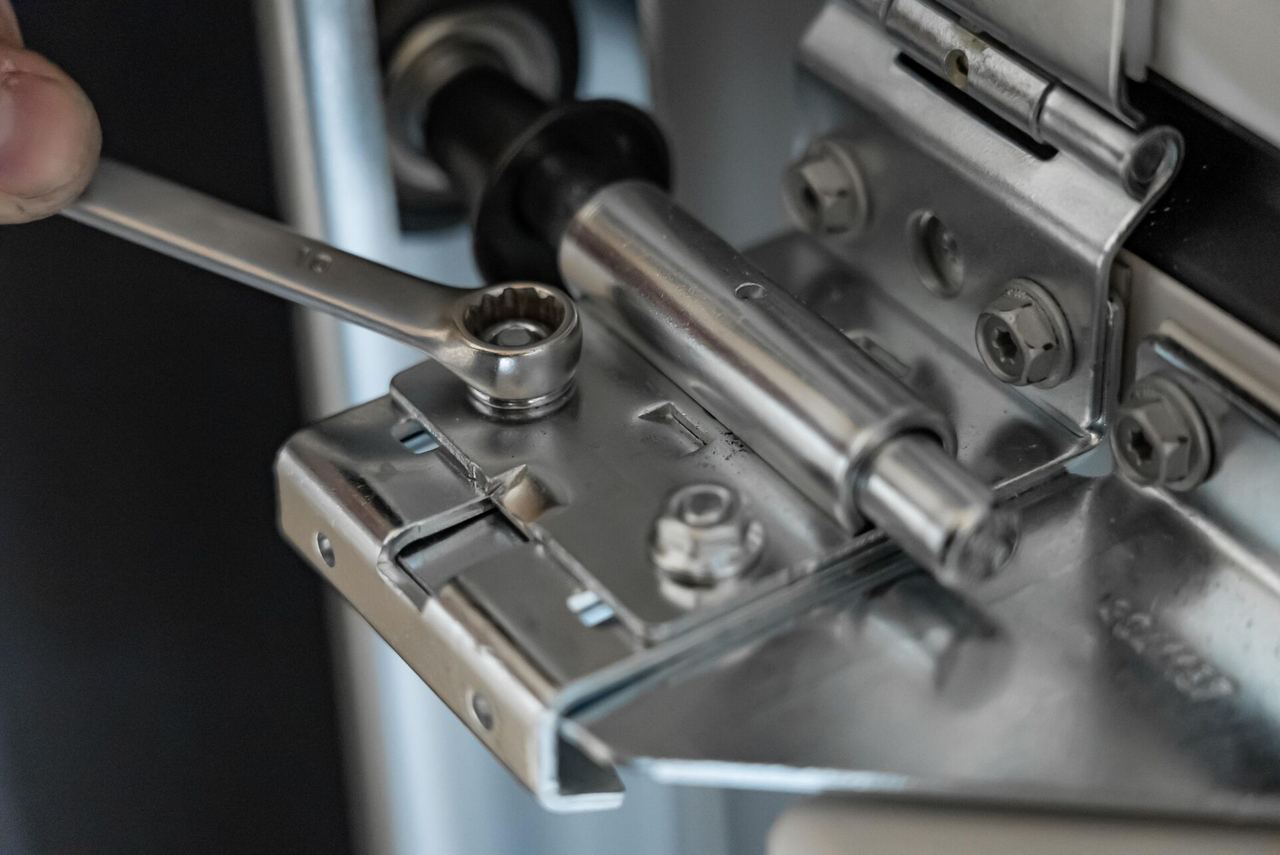 Close-up of a spanner adjusting the hinge and roller of a sectional garage door