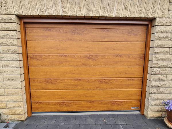 Geschlossenes Hörmann-Sektionaltor in Golden-Oak-Optik, Mauer aus hellem Sandstein
