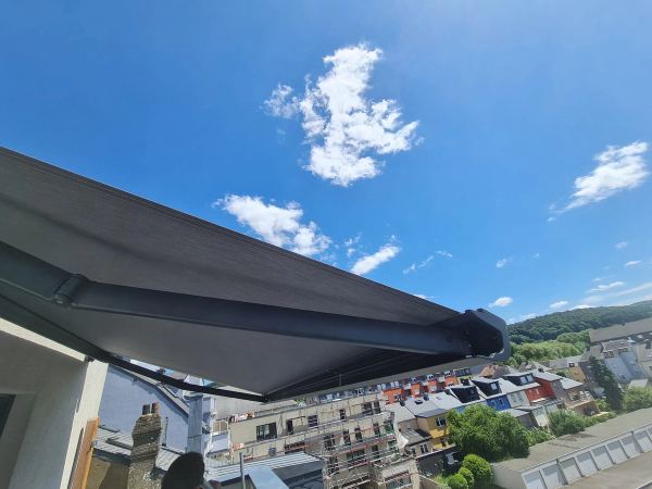 Anthrazit Markise von unten mit Blick über Dächer und bewaldeten Hügel