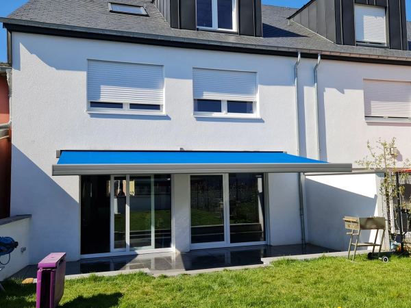 Leuchtend blaue Markise mit weißer Kassette am weißen Reihenhaus