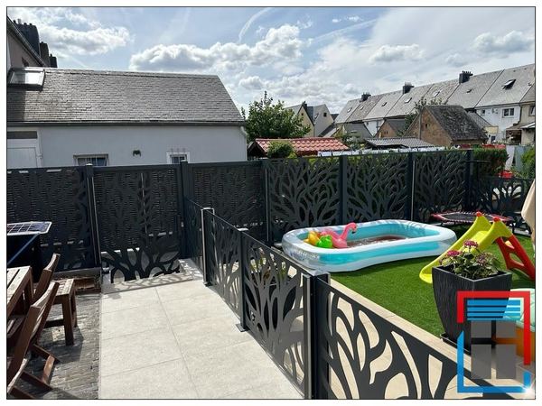 Anthrazitfarbene Sichtschutzpaneele mit Baummotiv um Terrasse und Garten mit Kinderspielzeug