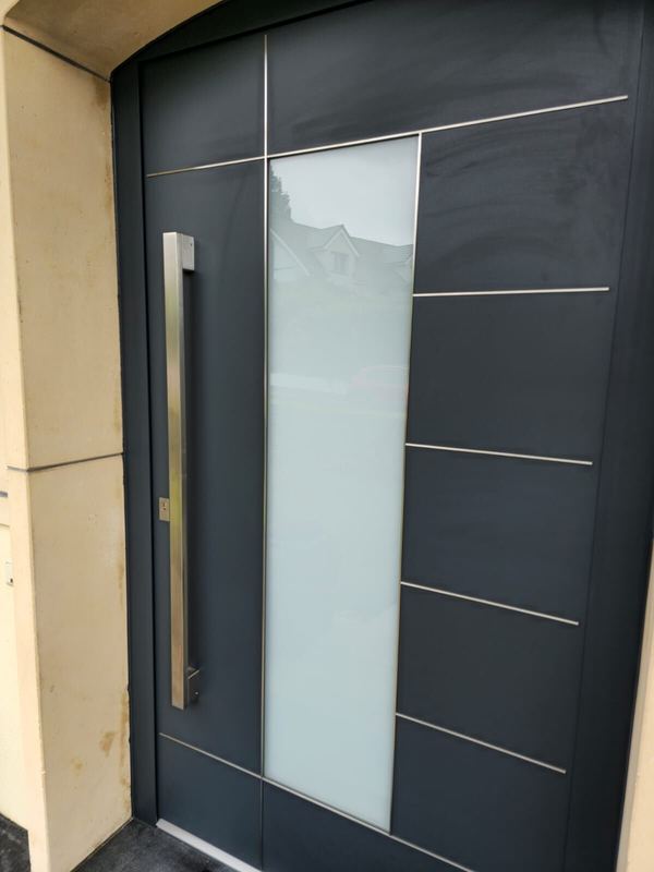 Nahaufnahme einer anthrazitfarbenen Haustür mit breitem Satinatoglas, Edelstahl-Lisenen und Vierkantgriff