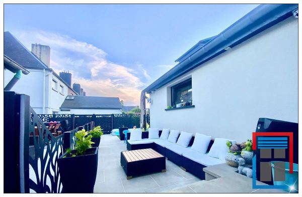 Terrasse mit Lounge-Möbeln, eingefasst von anthrazitfarbenen Sichtschutzpaneelen mit Blattmotiv