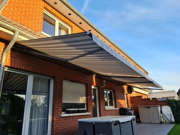 Grau gestreifte Markise an roter Klinkerfassade im Abendlicht