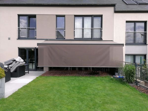 Taupefarbene Markise mit heruntergelassenem Screen-Volant vor Holzterrasse