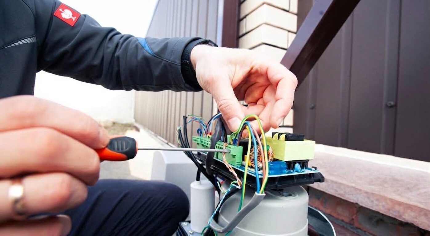 Technician reconnecting the wiring on the control board of a sliding gate motor