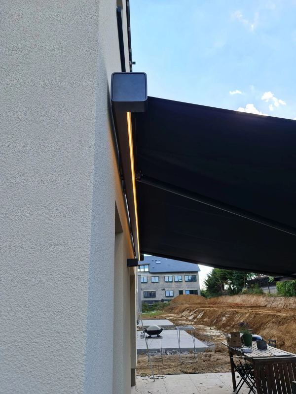Anthrazit Markise mit LED-Lichtleiste an weiß verputztem Neubau
