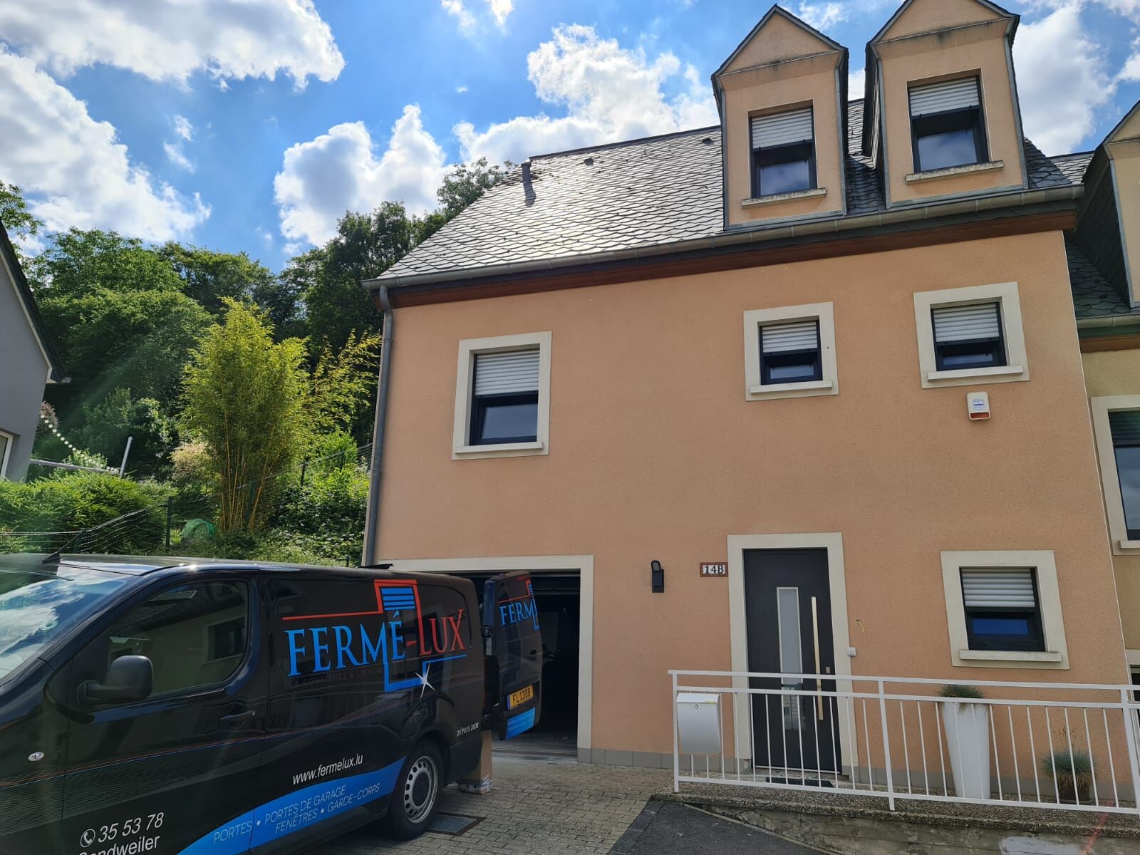 Haus mit lachsfarbener Fassade, anthrazitfarbenen Fenstern, Rollläden, Gauben und dunkelgrauer Haustür