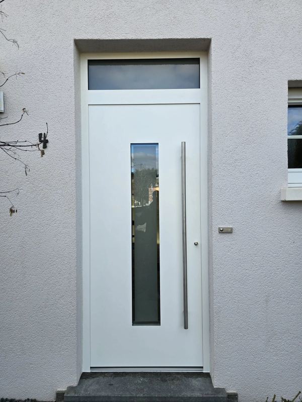 Weiße Haustür mit schmalem senkrechtem Glas, Oberlicht und langem Stangengriff an weißer Putzfassade