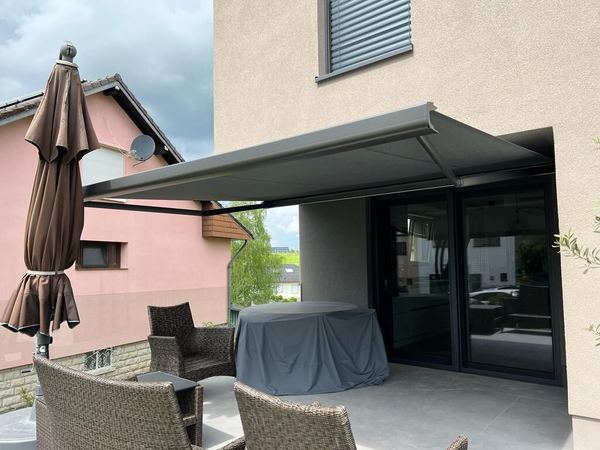 Anthrazit Kassettenmarkise ausgefahren über Terrasse mit Geflechtmöbeln
