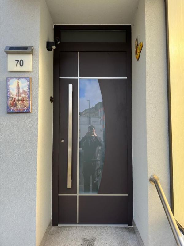 Dunkelbraune Haustür mit geschwungenem Glas, Oberlicht und Edelstahlgriff, Eingang mit Handlauf