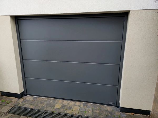 Glattes graphitgraues Sektionaltor mit 4 Paneelen, gebrochen weiße Putzfassade