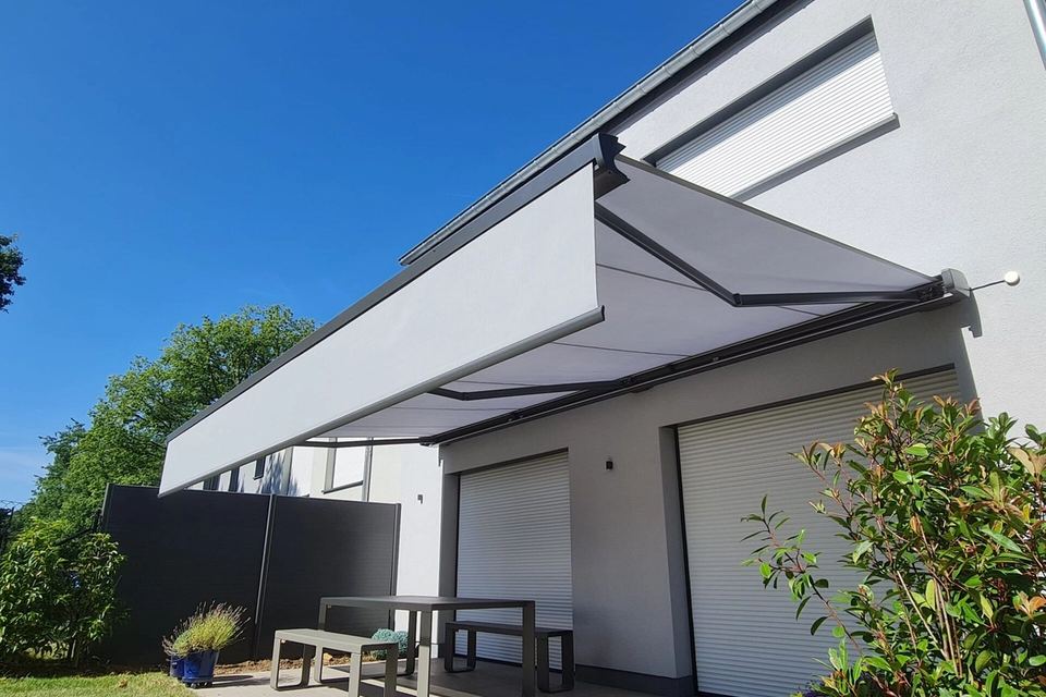 Light grey cassette awning with valance on a modern white house with roller shutters