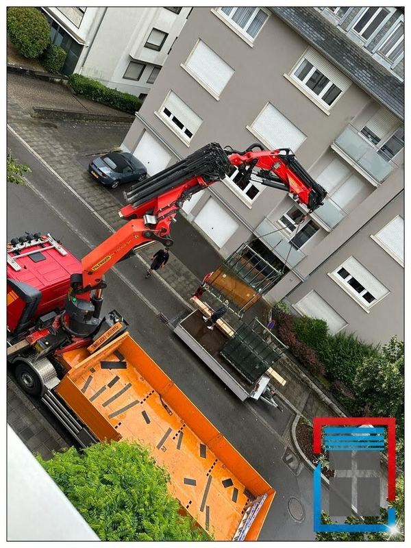Roter Ladekran hebt Glaselemente auf einem Gestell zum Obergeschoss eines Wohnhauses, Ansicht von oben