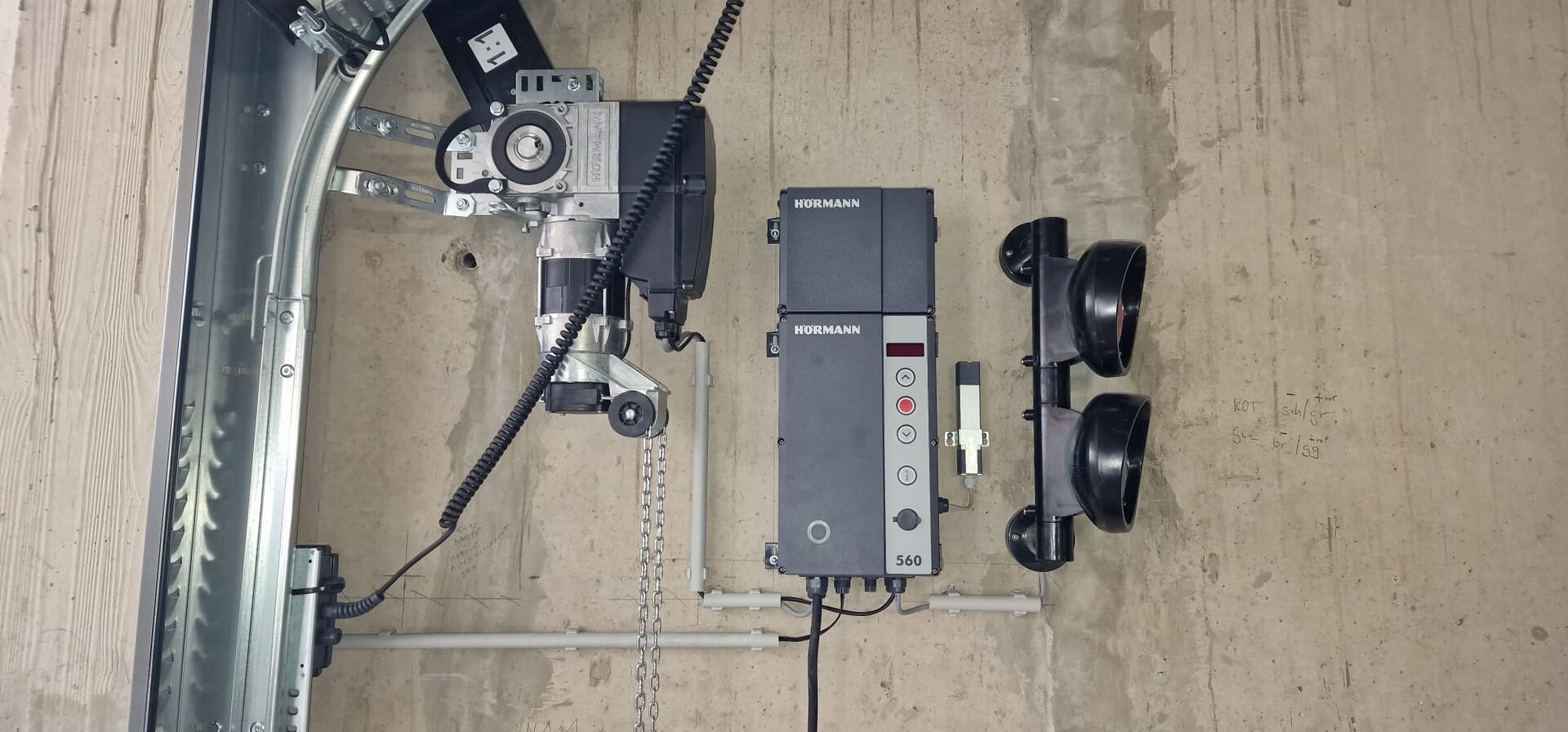 Motorisation industrielle et boîtier de commande Hörmann fixés au mur près du rail de la porte
