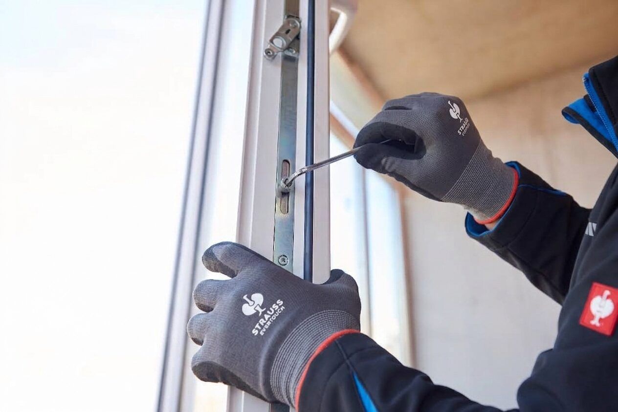 Techniker stellt mit einem Inbusschlüssel den Beschlag eines weißen Kunststofffensters ein
