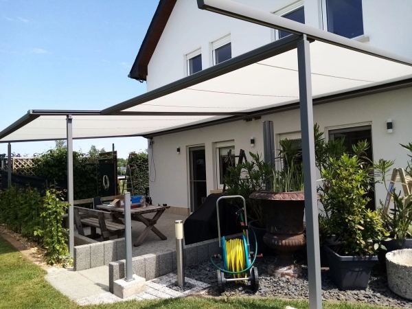 Weiße Pergolamarkise mit zwei Feldern auf Stützen über bepflanzter Terrasse