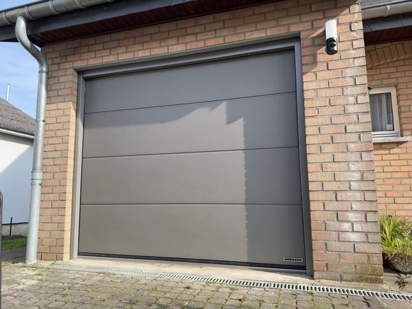 Graubraunes Hörmann-Sektionaltor mit breiten Sicken in einer roten Klinkerfassade