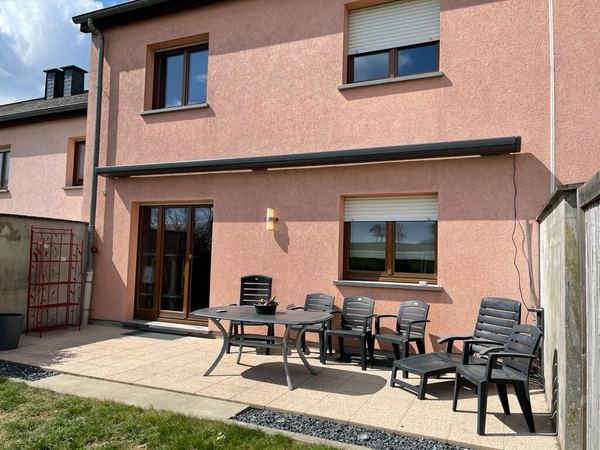 Geschlossene anthrazit Kassettenmarkise am rosa Haus über möblierter Terrasse