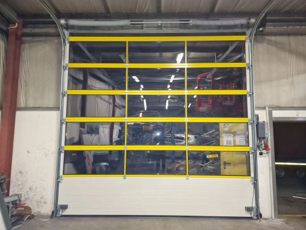 Industrie-Sektionaltor mit gelben Rahmen und großer Verglasung in einer Werkstatt