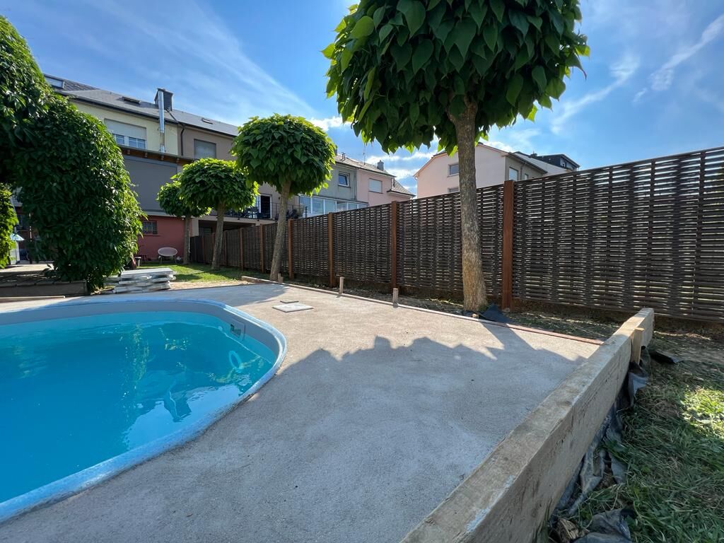 Brauner geflochtener Sichtschutzzaun mit rostfarbenen Pfosten um einen Garten mit Pool