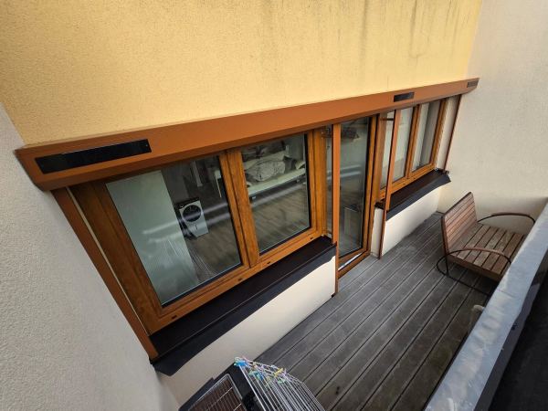 Fenster und Balkontür in Golden-Eiche-Optik auf einem Balkon mit Holzdielen, von oben gesehen