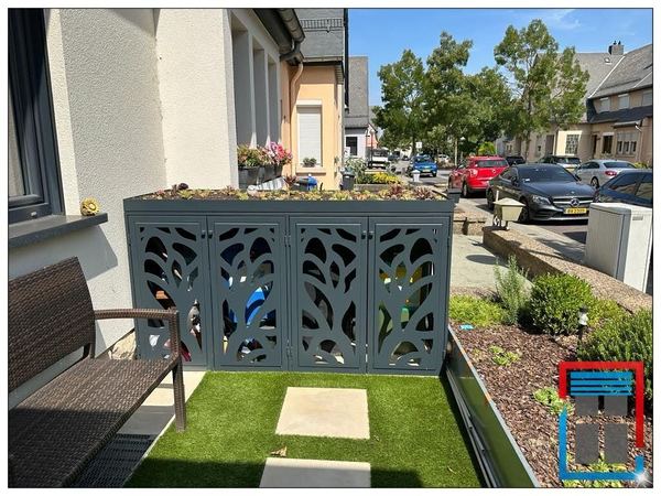 Anthrazitfarbene Mülltonnenbox mit Baummotiv-Lochblechtüren und begrüntem Dach im Vorgarten