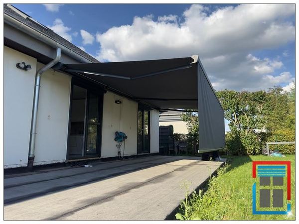 Große anthrazit Markise mit Volant am Bungalow, Wolkenhimmel und Rasen