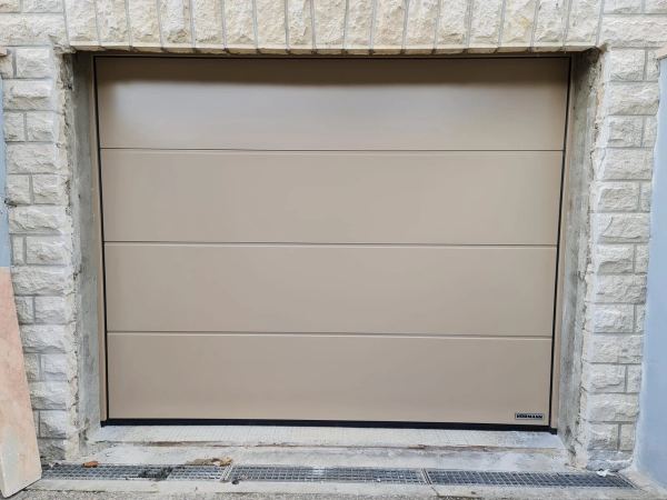 Glattes beiges Hörmann-Sektionaltor mit 4 Paneelen in einer Natursteinlaibung