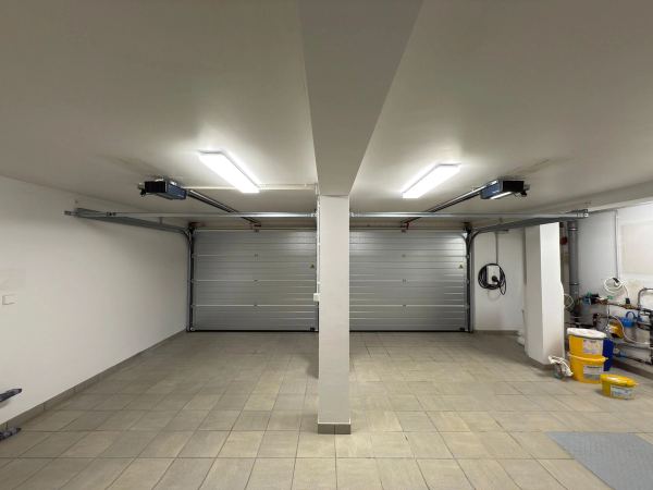 Innenansicht einer Doppelgarage: zwei silberne Sektionaltore mit Deckenantrieben