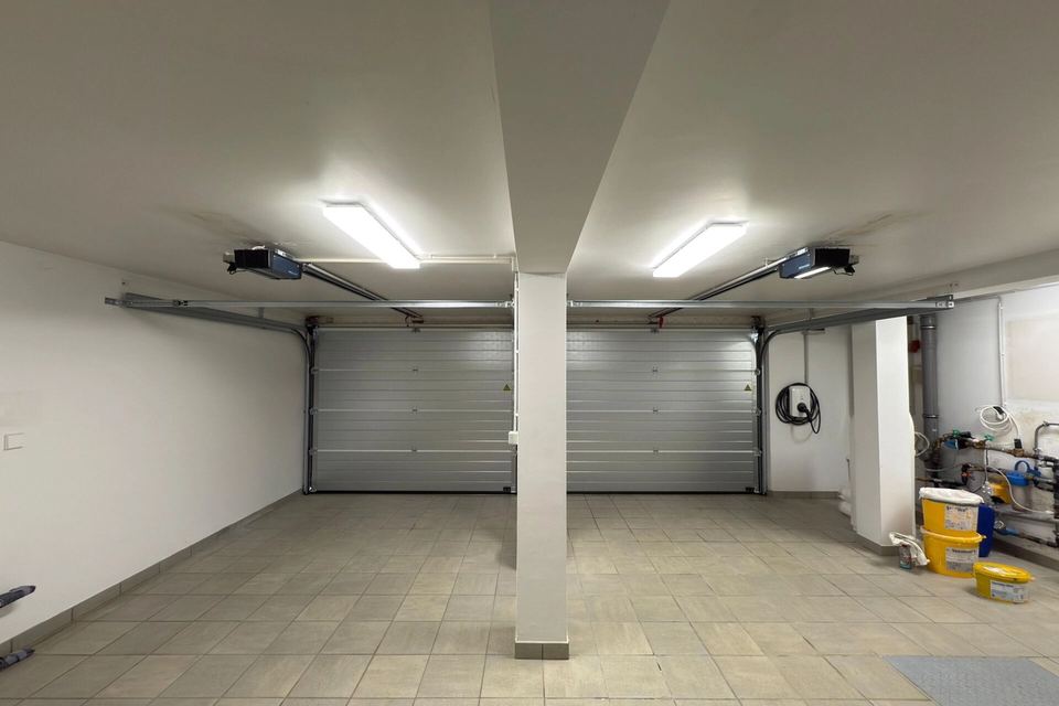 Intérieur d’un garage double : deux portes sectionnelles argentées avec motorisations au plafond
