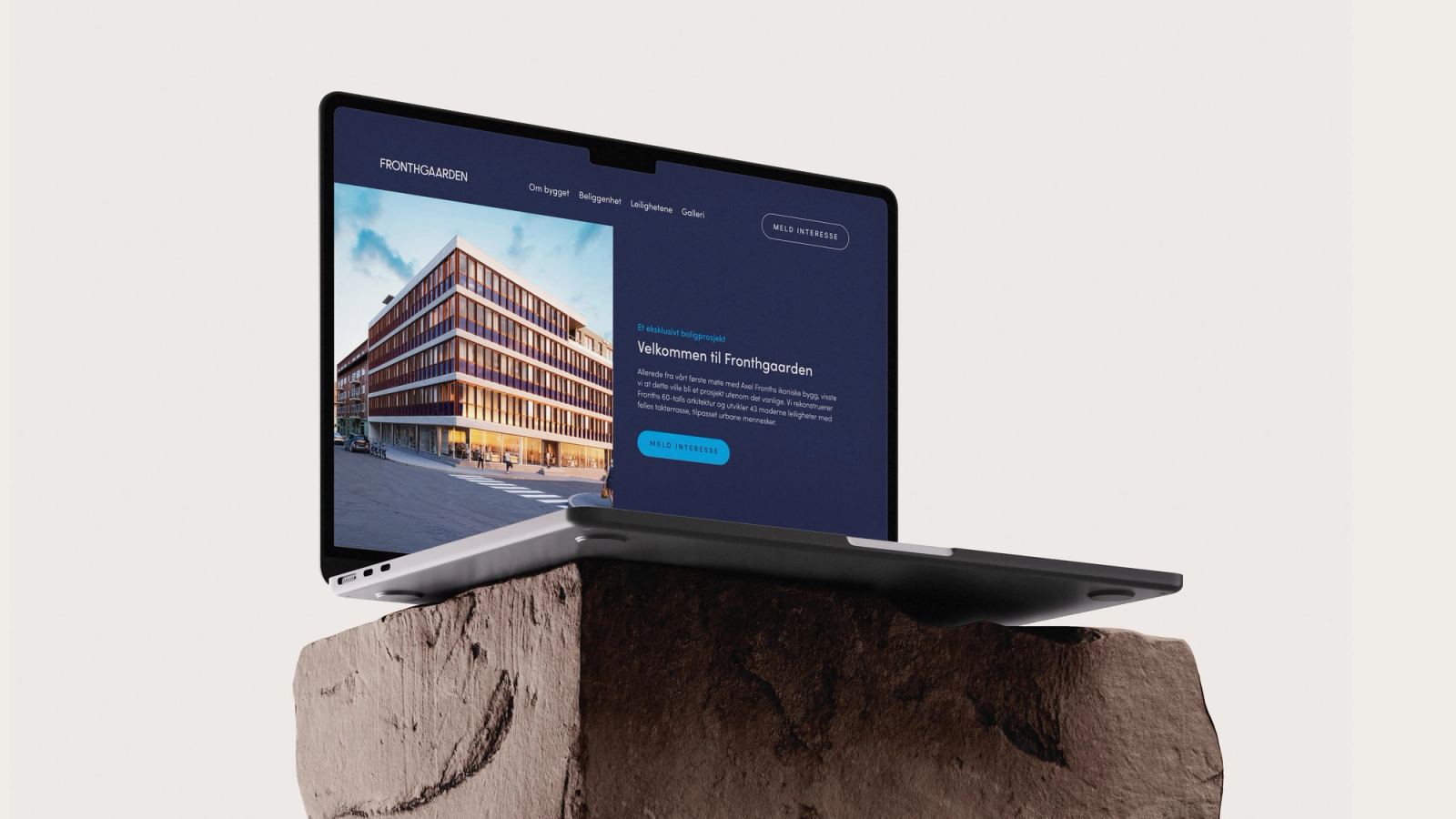 Laptop på en stein som viser Fronthgaarden sin nettside med bilde av boligbygget.
