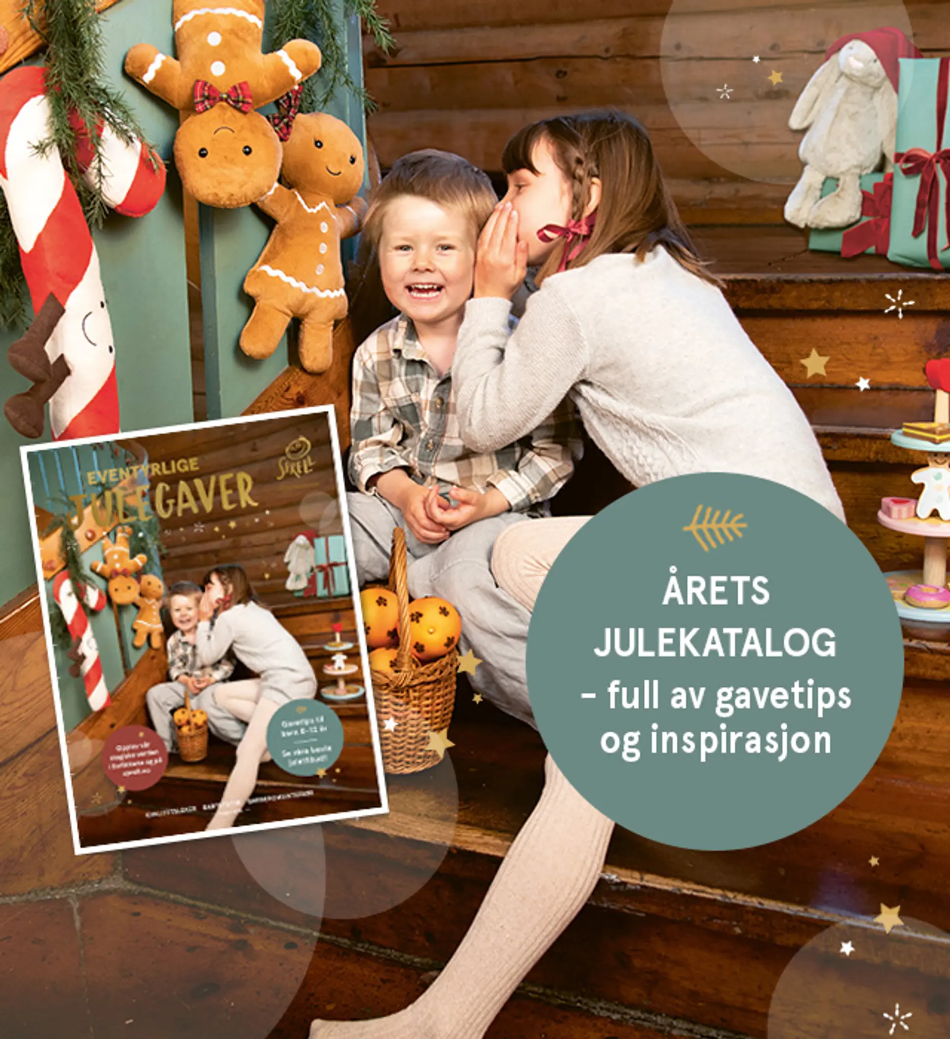 "Årets julekatalog er her - full av gavetips og inspirasjon!" Julekatalogen er avbildet over forsidebildet av to hviskende barn sittende i trapp med Jellycat Amuseables i bakgrunnen.