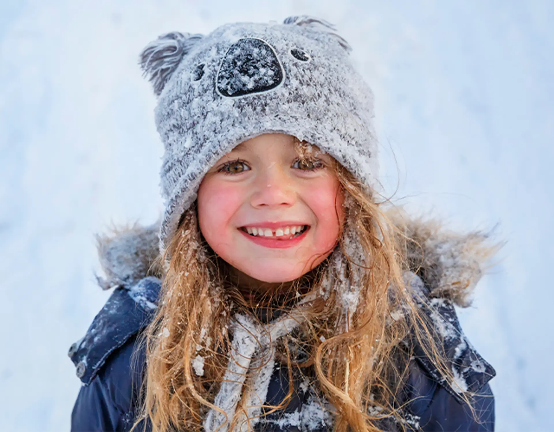 Fotografi av en smilende jente i snøen.