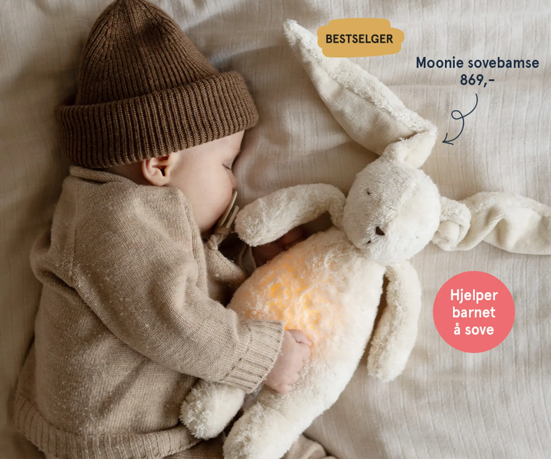 Fotografi av en sovende baby med en Moonie bamse i hendene. Bestselger - hjelper barnet å sove, 839 kr.